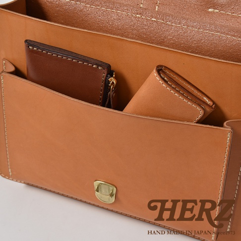 職人手作皮革三用單扣商務後背包，展示內部結構，可見兩個皮夾，一個為深棕色拉鍊皮夾，另一個為淺棕色皮夾，背包主體為淺棕色皮革。