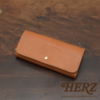 焦糖色皮革長夾，寬口設計，配有金色按扣與拉鍊，縫線精緻，展現職人手作質感。