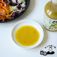 一個白色圓碟中盛有淺黃色、帶有細小顆粒的柚子風味沙拉醬，旁邊有一個玻璃瓶裝著同樣的沙拉醬，瓶身貼有日文標籤，描繪著柚子圖案。