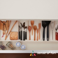 抽屜內整齊擺放著各式廚房用具，包含木質砧板、刨刀、不鏽鋼刀叉湯匙、木製湯勺、木叉、黑色鍋鏟、打蛋器，以及玻璃罐和圓形罐。