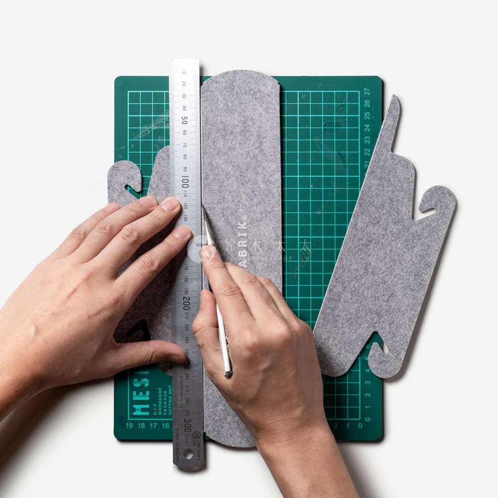 FABRIK 品牌圖案，手持尺和刀，在切割墊上沿著灰色毛氈布料裁切。
