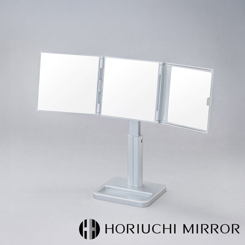 銀色金屬材質的桌上型三折化妝鏡，具有可調節高度的支架和方形底座，三面鏡面可依需求調整角度，方便全方位檢視。