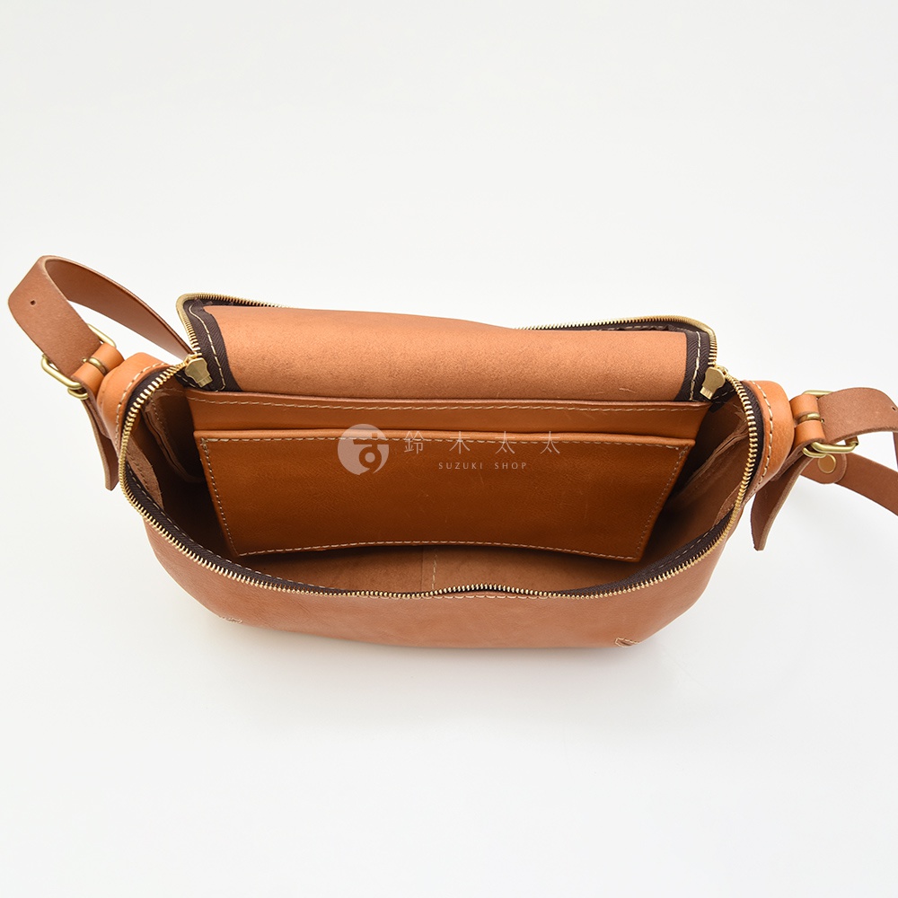 日本HERZ職人手作Stare皮革大容量馬鞍包CK-150，內部有夾層，整體為棕褐色，側背包視角，展示打開的內部空間，有SUZUKI SHOP的品牌標誌。