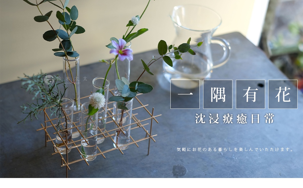 多格一輪玻璃花器，附有金屬支架，支架上插有六個玻璃試管，試管內有綠葉植物和紫色小花。