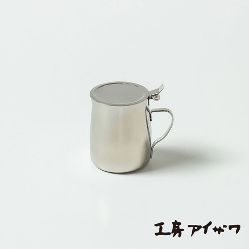 一個銀色不鏽鋼製的附蓋蜂蜜盅，有著圓潤的壺身和一個彎曲的提把，頂部有可開合的蓋子。