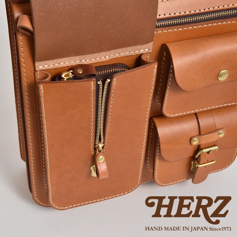 職人手作皮革三口袋三用後背包，淺棕色，以皮革製成，有多個拉鍊口袋和翻蓋式口袋，搭配黃銅色金屬扣環和拉鍊。