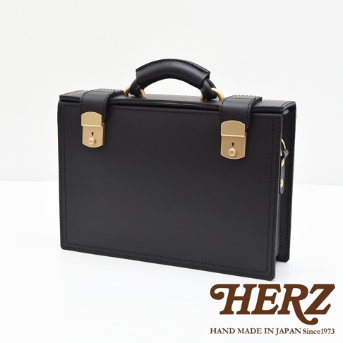 黑色皮革兩用機師箱，配有金色鎖扣及提把，簡約設計，展現職人手作質感。