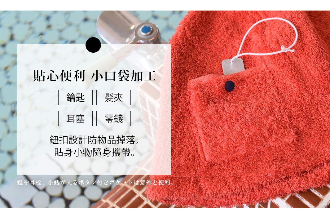 橘紅色毛巾，材質柔軟，設有鈕扣口袋，附有白色掛繩。