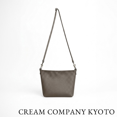 CREAM COMPANY KYOTO 品牌的灰色皮革側背包，採用柔軟輕量的牛皮製成，外型簡約並配有細長可調節背帶，適合日常隨身收納。