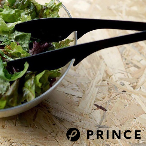 一雙黑色料理夾，前端呈勺狀，夾取碗中的沙拉。