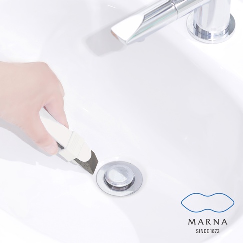 手持白色萬用去污橡皮擦，其深灰色海綿狀去污端正靠近白色水槽的排水孔，水槽為陶瓷材質，上方有鉻合金水龍頭。