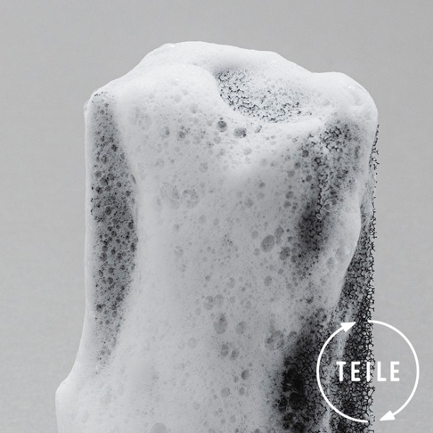 廚房潔淨固體皂，黑色海綿狀材質，表面覆蓋豐富細密的白色泡沫，角落有圓形白色標示，內含「TEILE」文字與循環箭頭。