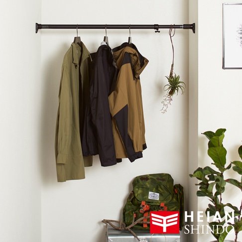 黑色兩段式伸縮桿，掛有三件不同顏色外套，左側為軍綠色長袖外套，中間為黑色外套，右側為卡其色與黑色拼接外套。