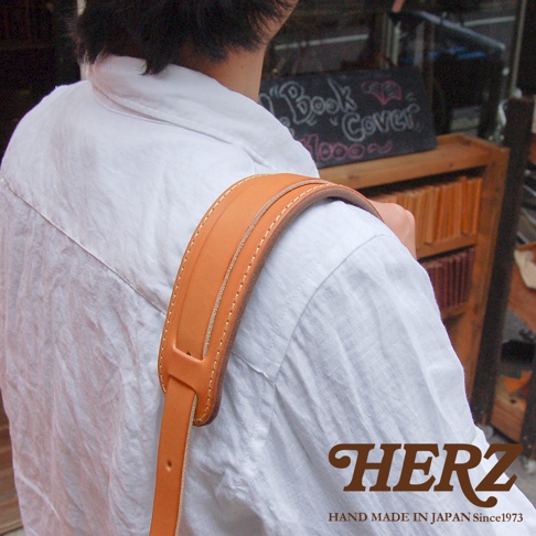 職人手作皮革Big肩墊，採用天然皮革製作，顏色為淺棕色，設有縫線裝飾，並可調節長度。