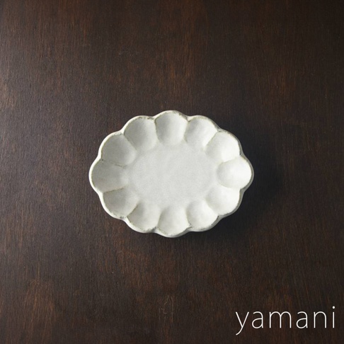 一個18公分的白色六魯粉引花型橢圓料理盤，盤緣有明顯的花瓣狀凹凸紋路，整體呈現質樸的手工質感，置於深棕色木紋背景上。