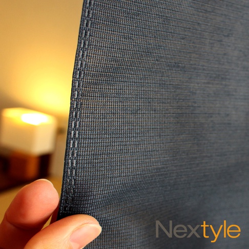 深灰色網狀材質的門簾，帶有清晰的縫線邊緣，背景有模糊的暖色光源。