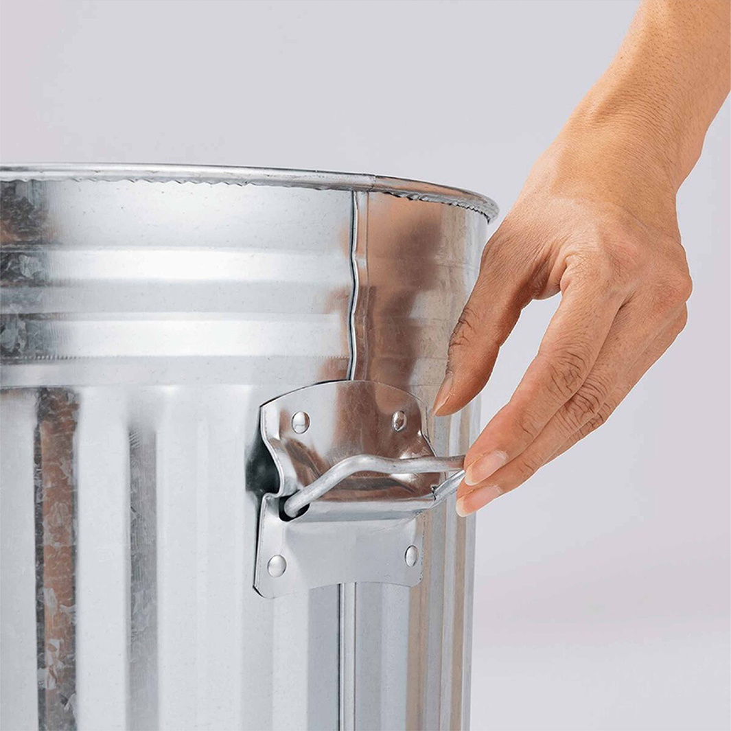 一只手正要關上一個金屬垃圾桶的蓋子，這個垃圾桶是手工製作的，容量為 42 公升。