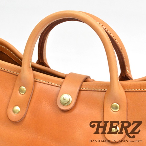 職人手作皮革大容量托特包 T-146，展示包款的棕褐色牛皮材質，以及精緻的縫線與金屬釦細節。