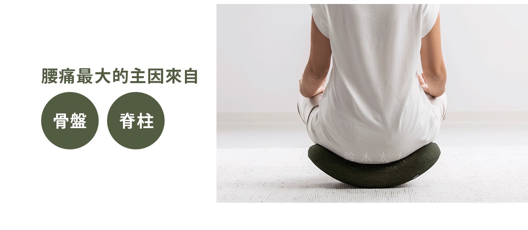 深綠色U型搖搖枕，材質為布料，中間有縫線，置於白色地毯上，一位身穿白色上衣和褲子的人盤腿坐於其上。