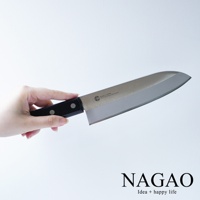 手持一把燕三條 VG-10 不鏽鋼三德刀，刀刃為銀色鏡面不鏽鋼，刀柄為黑色，上面刻有「MADE IN JAPAN」及「VG-10 Core Stainless Steel Layered」字樣。