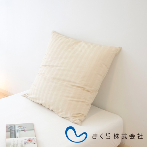 淺米色條紋提花枕套，內含方枕，置於白色床鋪上，背景為白色牆壁。