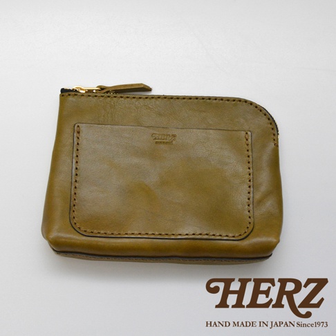 職人手作橄欖綠皮革小物收納包，側面有拉鍊，正面有一個方形外袋，袋上有品牌燙金標誌。