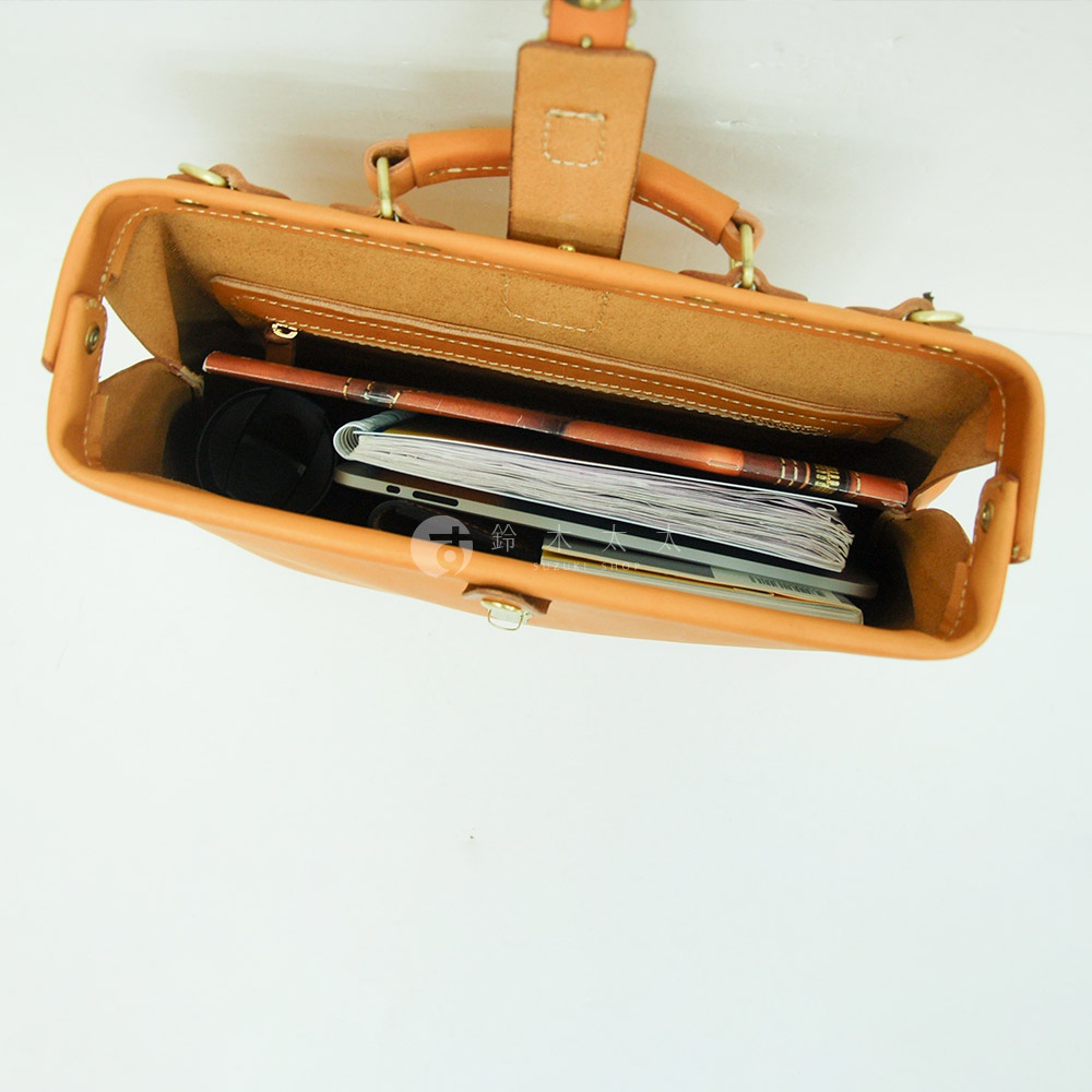 職人手作皮革軟式杜勒斯包，淺棕色，展示包內裝有筆記本、文件、手機和筆。