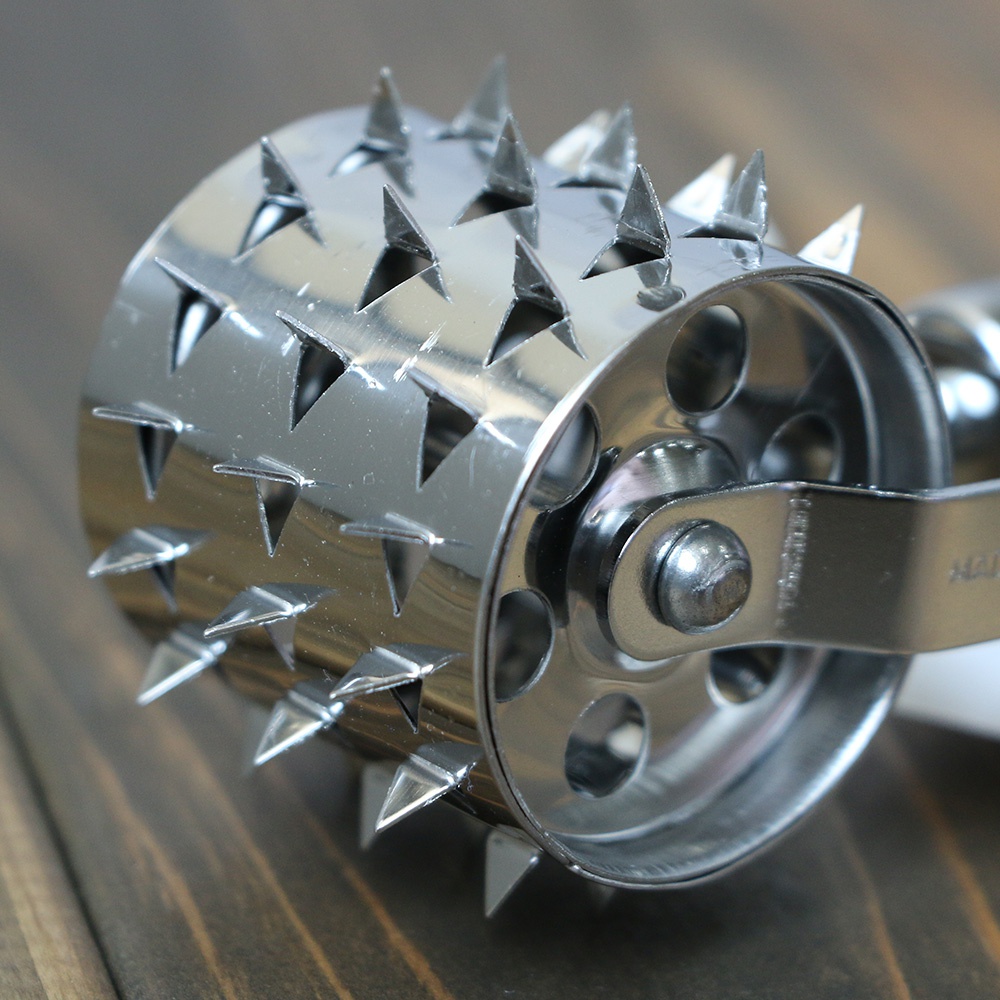 不鏽鋼製的滾輪斷筋器，滾輪表面佈滿三角形尖刺，側面有圓形孔洞，整體呈現金屬光澤。