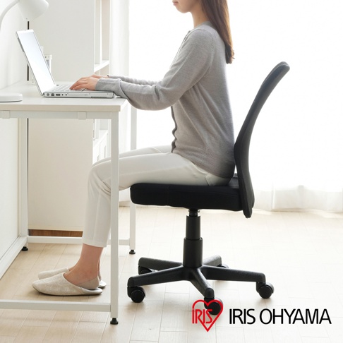 一名女子坐在辦公椅上，手放在筆記型電腦的鍵盤上，桌子旁邊有書架。