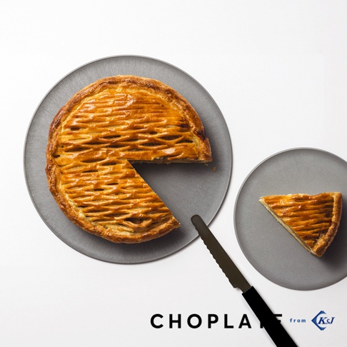CHOPLATE兩用砧板盤，灰色圓盤上放有烤製金黃色網狀派皮的圓形派，派已切下一塊。旁邊另有一個較小的灰色圓盤，盤上放著一片派。一把黑色刀具橫亙在兩盤之間。
