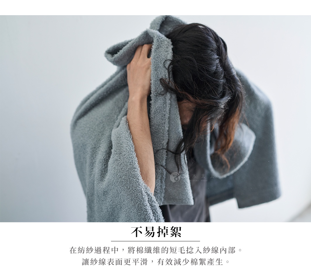 一個人正在用灰色毛巾擦拭頭髮，毛巾質感蓬鬆柔軟。