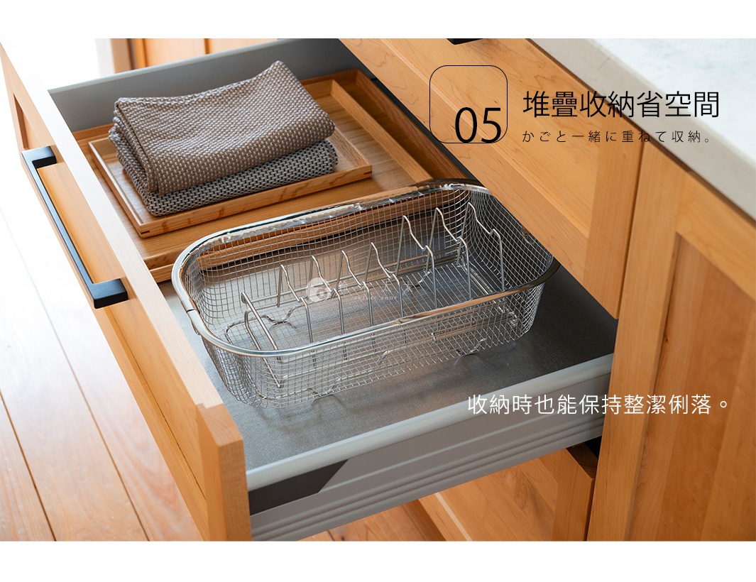 抽出式木製櫥櫃內，一個不鏽鋼瀝水籃裝著碗盤，旁邊堆疊著毛巾。