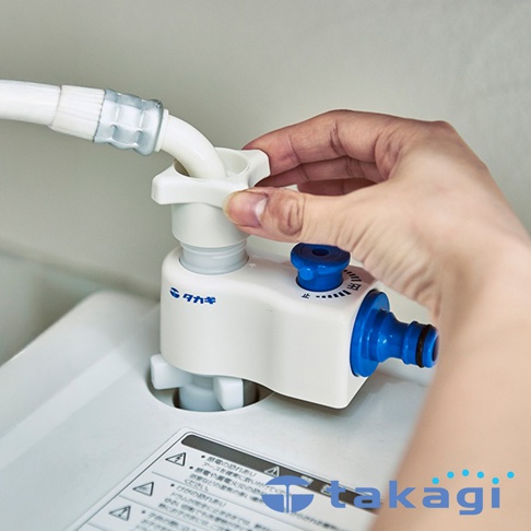 takagi 洗衣機分水轉接頭，一個白色的轉接頭，上面有藍色的旋鈕和水龍頭接口，手正在將白色水管連接到轉接頭上。