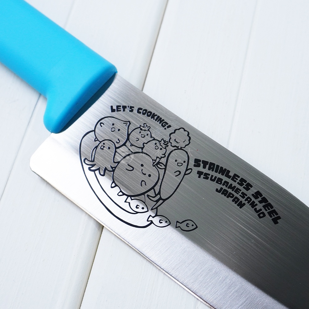燕三條不鏽鋼兒童學習刀，刀柄為淺藍色，刀身上印有「LET'S COOKING!」字樣以及可愛的蔬菜卡通圖案與魚圖案，並標示「STAINLESS STEEL TSUBAMESANJO JAPAN」。