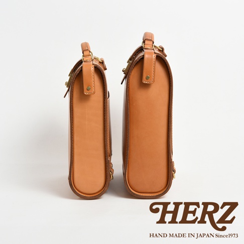 兩款淺棕色皮革後背包，款式經典，材質為真皮，搭配金屬扣環，呈現簡約的商務風格。