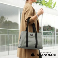 京都職人手作Sarei機能布中型口金托特包，灰色托特包搭配黑色背帶，一位女性身穿駝色外套斜背著此包款，包款左側有AYANOKOJI品牌標誌。