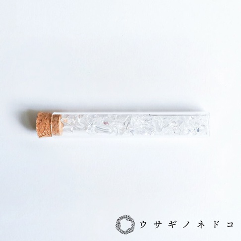 玻璃試管瓶裝有透明的碎裂礦石，瓶口以軟木塞封閉。
