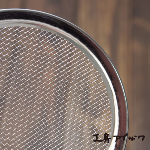 不鏽鋼萬用撈油勺的圓形網篩，網孔細密，邊緣為光滑金屬亮面。