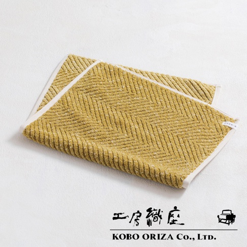 黃色棉麻混紡人字紋浴墊，帶有白色滾邊，質地柔軟。