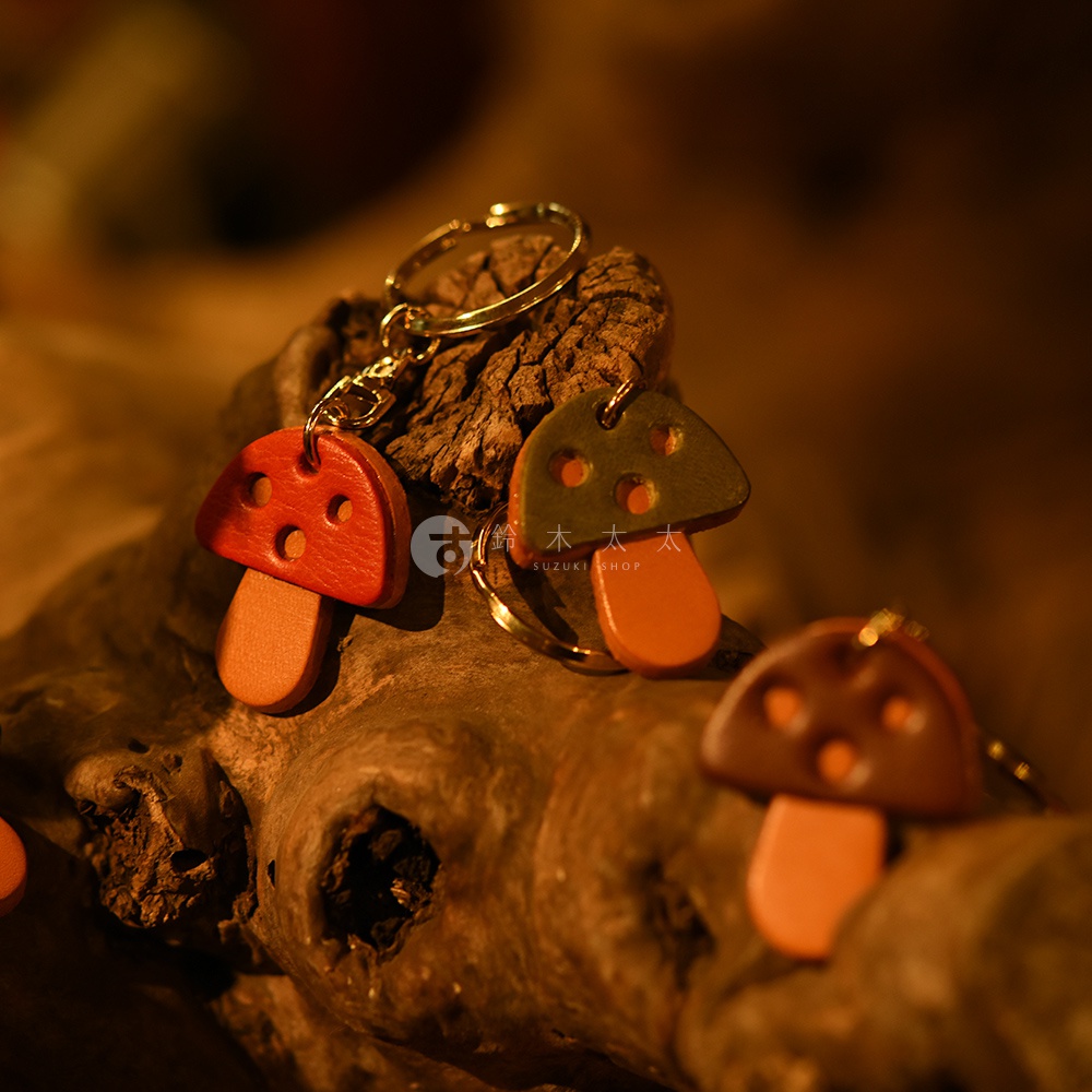 職人手作皮革香菇造型鑰匙圈，有紅色、綠色、棕色等多種顏色，造型可愛，材質為皮革，搭配金屬鑰匙圈環。