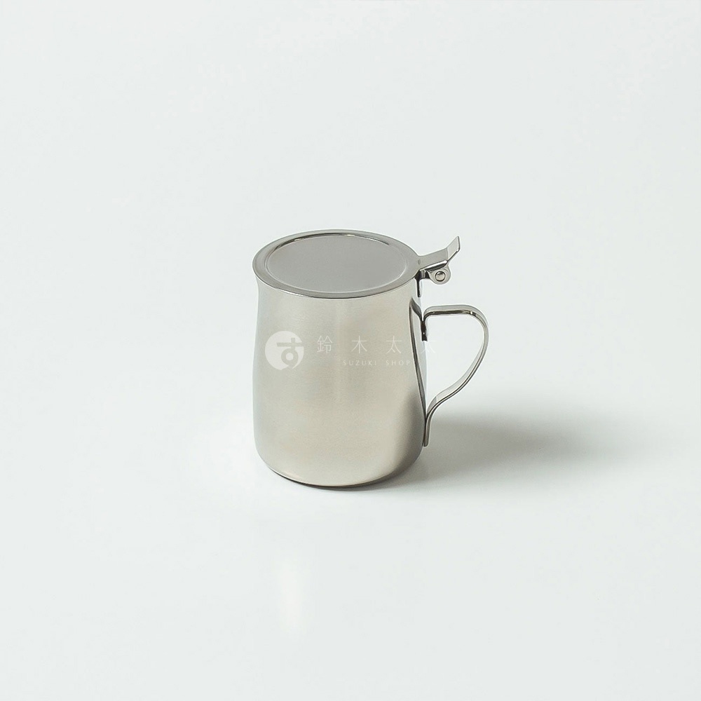 一個銀色不鏽鋼附蓋蜂蜜盅，帶有一個方便開啟的壓扣式蓋子和一個彎曲的把手。