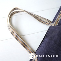 深藍色蚊帳棉織隨身購物袋，配有米白色織帶提把，提把上飾有藍色和橘色條紋。