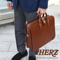 職人手作棕色皮革三層收納兩用商務公事包，配有金色金屬拉鍊、旋轉鎖扣和可拆卸肩帶。