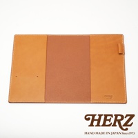 職人手作皮革B6記事本書套，採用棕色皮革，內有兩個卡槽，表面有明顯的縫線，右側有一條皮革束帶。