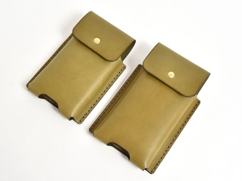兩個橄欖綠皮革手機收納包，均配有金色按扣和縫線細節。