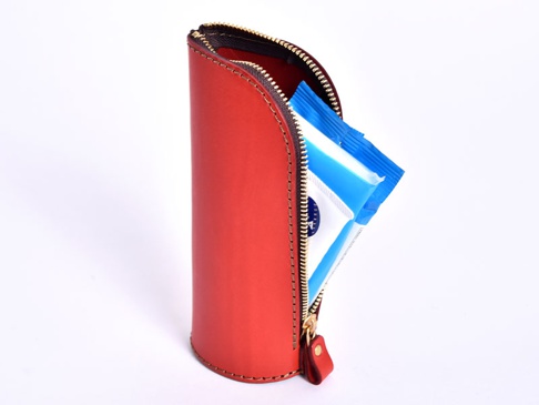 職人手作紅色皮革直立式收納筆袋，拉鍊開啟，露出內側兩包藍色包裝的物品。