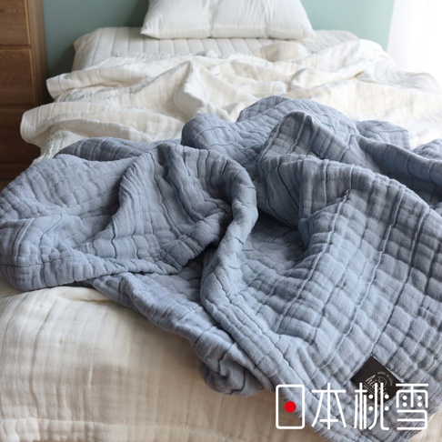 淺藍色八層紗透氣被，材質輕盈，表面有網格狀紋理，鋪蓋在白色床鋪上，角落處可見黑色品牌標籤。