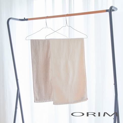 兩條 BISAI 今治浴巾，一條為米色，一條為淺米色，皆為純棉材質，掛在衣架上，背景為白色窗簾。