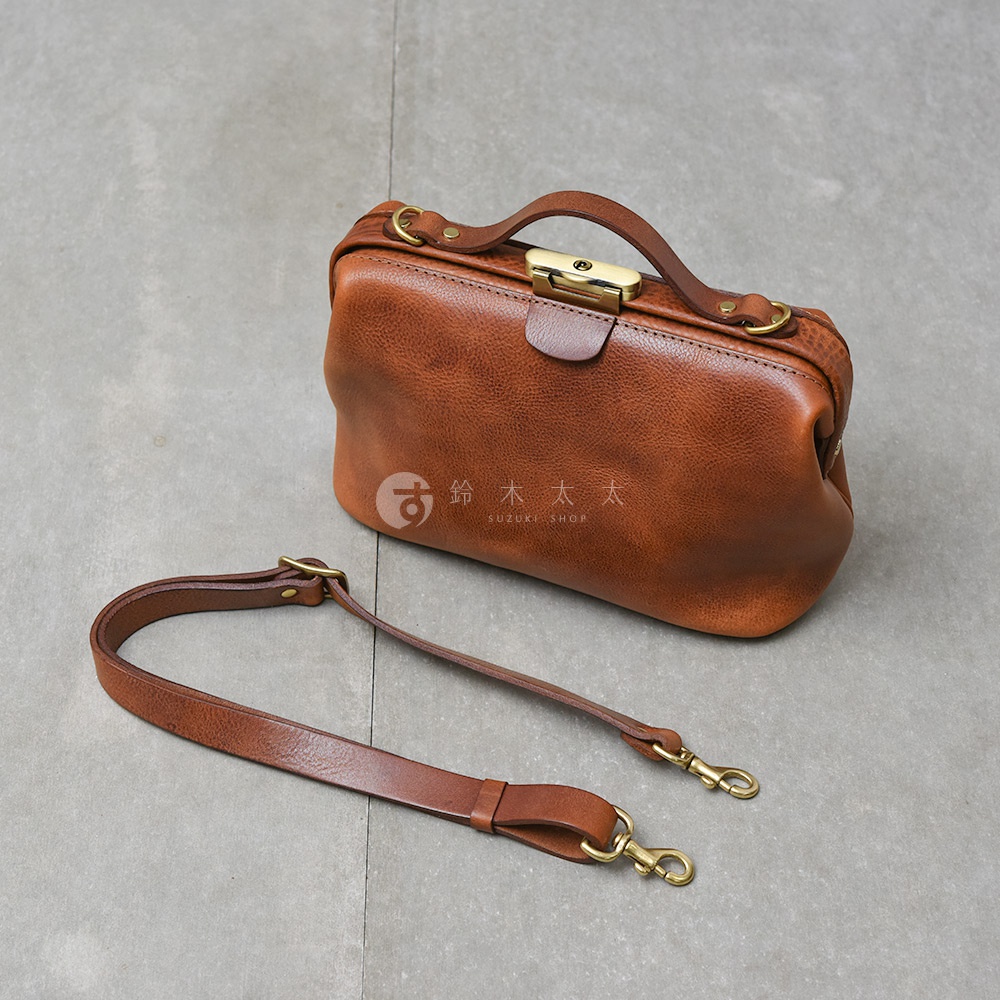 日本製 HERZ Organ 鎖孔式皮革肩背包，採用棕色皮革製作，搭配金屬鎖頭和可拆卸肩帶，展現職人手作質感。