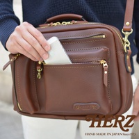 職人手作皮革兩用多功能收納單肩包，咖啡色牛皮材質，設有金色拉鍊和多個收納隔層，可斜挎或手提。
